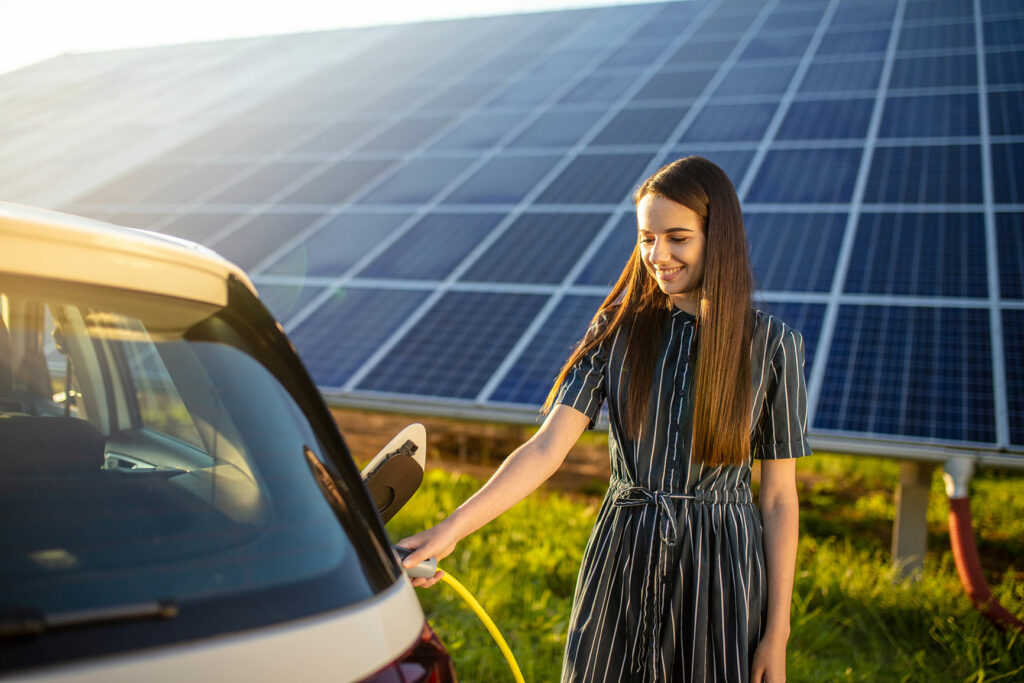 Frau lädt Elektroauto an Ladestation mit Photovoltaik